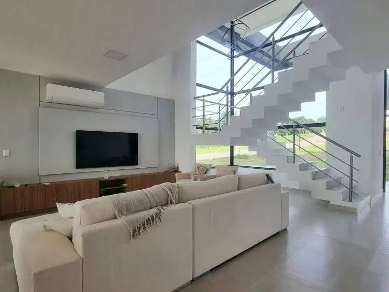 Sala de estar acabada, com escada e amplas esquadrias de vidro